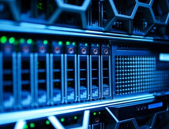Server-Racks mit blauer Beleuchtung, Frontpaneele mit Laufwerkschächten, Lüftungsgitter und Netzwerkausrüstung.