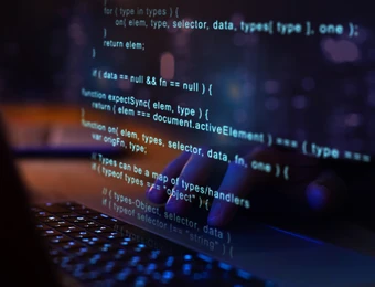 Blauer Code auf dunklem Bildschirm; Tastatur unten, Programmierzeilen sichtbar.