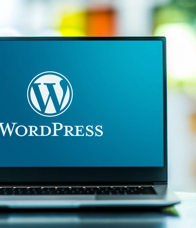 Laptop auf einem Tisch, blauer Bildschirm mit WordPress-Logo und dem Schriftzug WordPress.