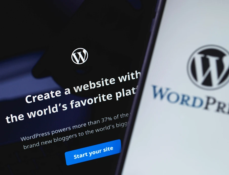 Zwei Bildschirme mit WordPress-Logo; linker Bildschirm Textzeile und blauem Button, rechter Bildschirm WordPress-Wortmarke.