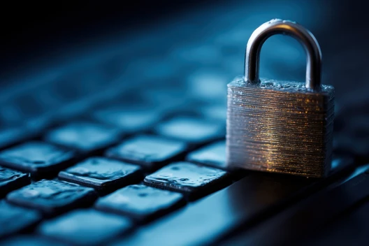 Nahaufnahme eines Metallvorhängeschlosses auf einer Tastatur, blau beleuchtet.